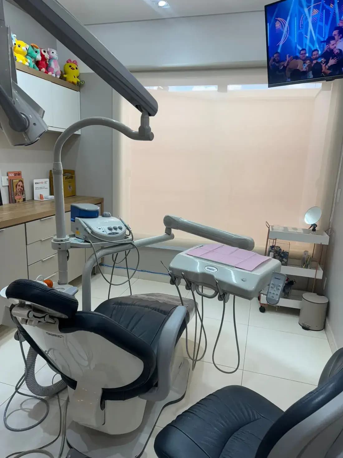 Sala de atendimento com cadeira odontológica, refletor e janela